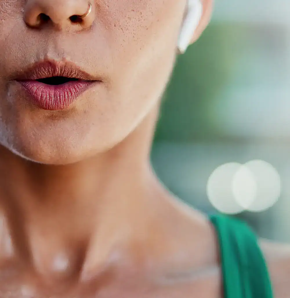 Frau mit Nasenpiercing und Earbuds führt Atemübungen durch – Ayurveda-Therapie bei Bronchitis