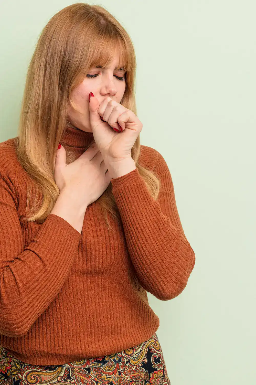 Frau mit Bronchitis hustet in die Faust – Ayurveda Behandlung bei RoSana kann helfen