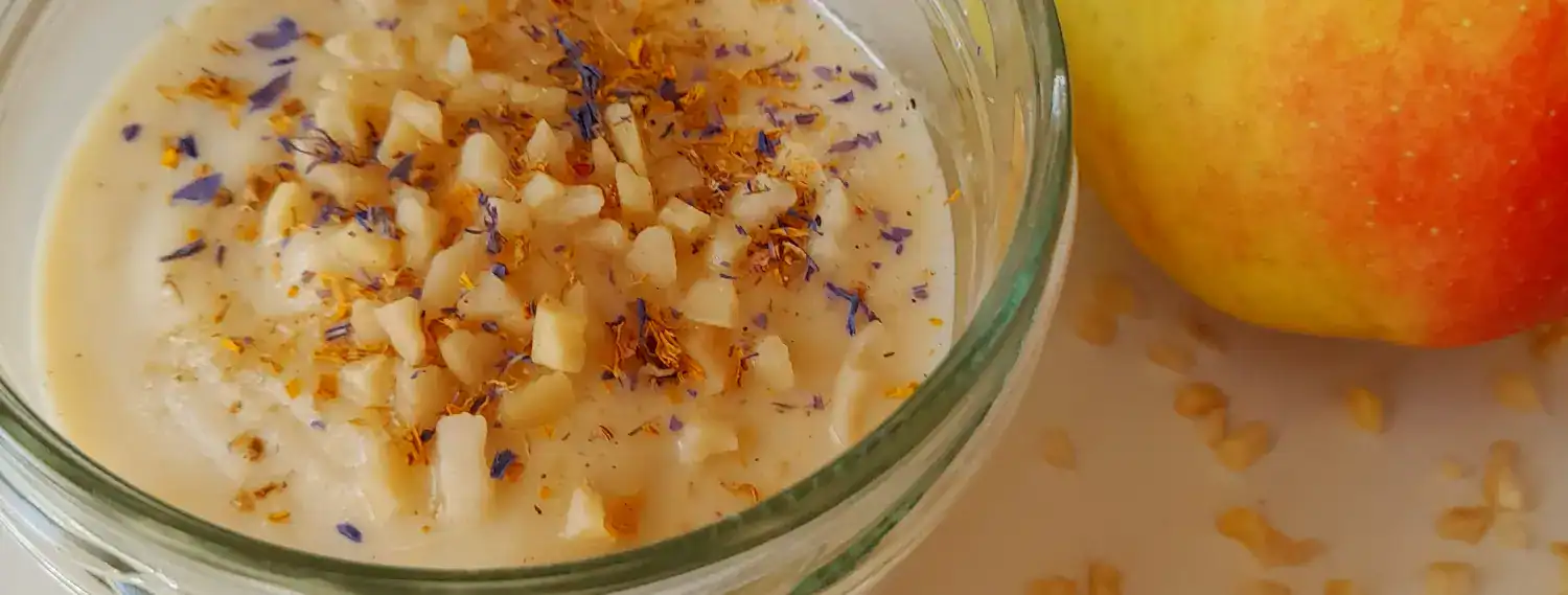 Apfel-Mandelcreme Banner Ayurvedische Apfel-Mandelcreme mit Lavendelblüten und Gewürzen im Glas, daneben ein frischer Apfel